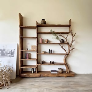 Op de afbeelding: Een rustieke houten boekenkast met een uniek boomachtig ontwerp. De planken zijn gevuld met decoratieve items, waaronder boeken, vazen en kleine sculpturen. De natuurlijke houtnerf en organische vorm creëren een warme, uitnodigende esthetiek. Een blikvanger voor elk huis.