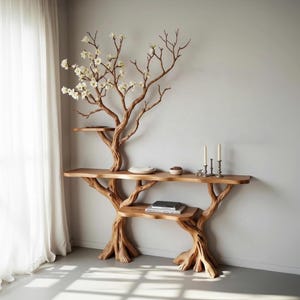 Puede incluir: Una consola de madera con un diseño de árbol. La mesa tiene tres estantes y está adornada con una rama florida artificial. Dos velas y un cuenco pequeño están en el estante superior. La mesa es de madera de color marrón claro.