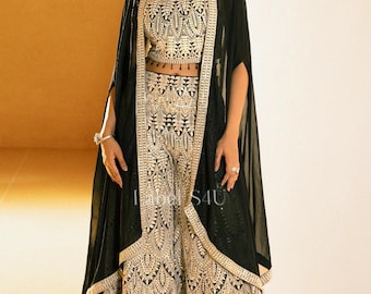 May include: A formal black and gold embroidered outfit. The ensemble includes a crop top, palazzo pants, and a long cape. The intricate gold embroidery creates a striking contrast against the black fabric, offering a luxurious look.