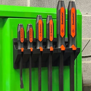 Könnte beinhalten: Ein Set aus sechs schwarzen und orangefarbenen Dominator-Brechstangen, die in einer schwarzen Wandhalterung angeordnet sind. Jedes Werkzeug verfügt über einen strukturierten Griff mit dem Wort Dominator auf orangefarbenem Grund.