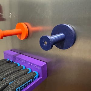 May include: A purple magnetic screwdriver holder with several screwdrivers and two magnetic hooks. The screwdrivers have black and blue handles. The hooks are orange and blue. The text "ICON" is visible on the screwdriver handles.