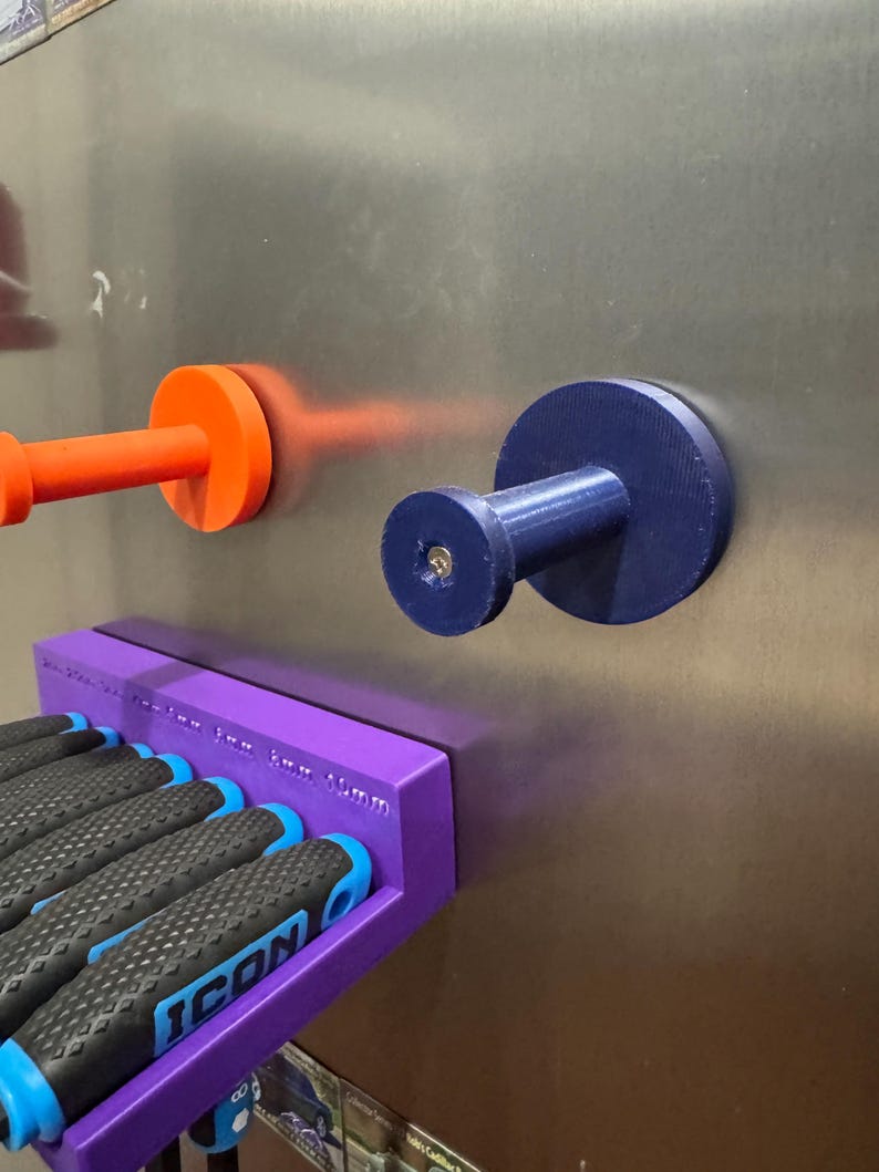 May include: A purple magnetic screwdriver holder with several screwdrivers and two magnetic hooks. The screwdrivers have black and blue handles. The hooks are orange and blue. The text "ICON" is visible on the screwdriver handles.