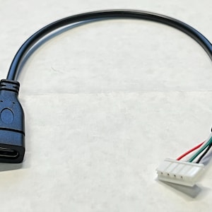 Puede incluir: Un cable USB negro con un conector USB-C en un extremo y un conector de 4 pines en el otro extremo.