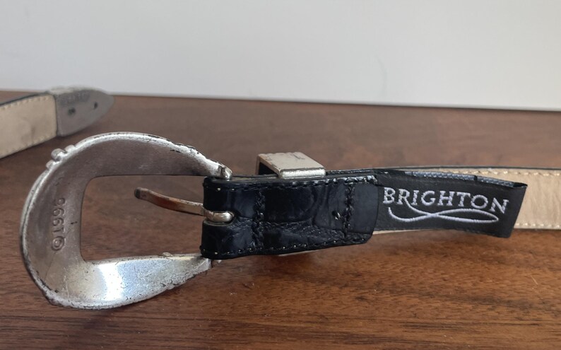 Pu&ograve; includere: Una tazza di ceramica bianca con manico nero e la scritta "But First, Coffee" in grassetto nero. La tazza &egrave; posta su uno sfondo sfocato, che suggerisce un'atmosfera accogliente.