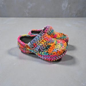 May include: A pair of brightly coloured crochet clogs. The clogs are crafted with a variety of vibrant hues, including pink, orange, yellow, blue, and green. The crochet work is detailed and covers the entire shoe.