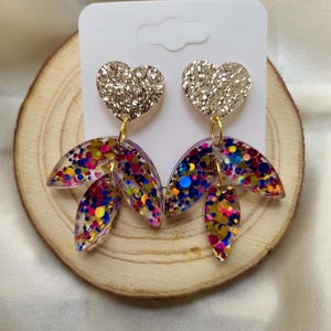 May include: Gold glitter heart dangle earrings with clear resin leaves filled with colourful confetti.