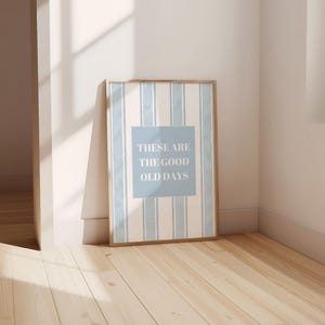 May include: A framed print with a blue and white striped background and the text "These are the good old days" in a white box.