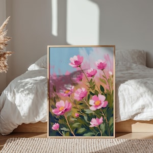 May include: A framed floral painting featuring vibrant pink flowers with yellow centers against a backdrop of blue and pink brushstrokes. The artwork is set in a gold frame, creating a decorative piece for home decor.