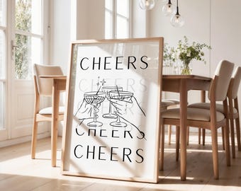 Könnte beinhalten: Ein gerahmter Druck mit dem Wort "CHEERS" in fetter, schwarzer Schrift wiederholt. Der Druck zeigt eine Strichzeichnung von Händen, die mit Cocktailgläsern anstoßen. Das Kunstwerk wird in einem Esszimmer mit einem Holztisch und Stühlen ausgestellt.