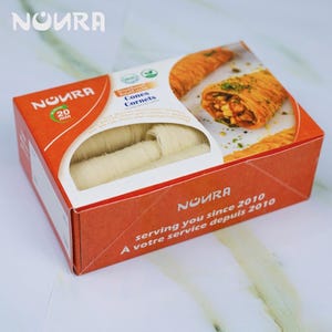 May include: A box of white pastry cones, called "Cones Cornets", from the brand "NOURA". The box is orange and white with the brand name and the text "serving you since 2010, À votre service depuis 2010".
