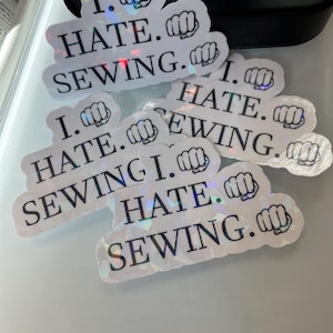 May include: Five iridescent stickers with the text "I. HATE. SEWING." and a fist emoji.