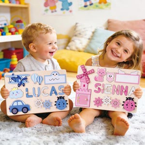 Puede incluir: Dos niños sostienen rompecabezas de nombres de madera. Uno deletrea "LUCAS" en letras azules con un coche, un avión y otras formas. El otro deletrea "SIENNA" en letras rosas con un molino, un castillo y otras formas.