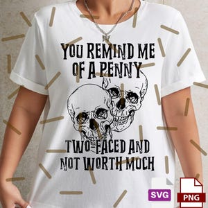 May include: White t-shirt with a black graphic of two skulls and the text "YOU REMIND ME OF A PENNY TWO-FACED AND NOT WORTH MUCH." The shirt also includes SVG and PNG file type icons.