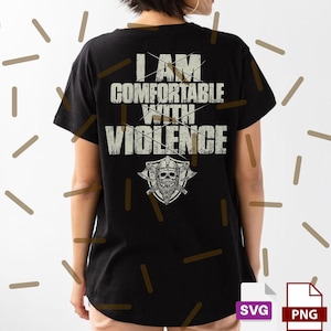 May include: Black t-shirt with the text "I AM COMFORTABLE WITH VIOLENCE" in a distressed white font. A Viking skull graphic with crossed axes is below the text. The shirt is a casual wear item.