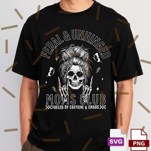 Puede incluir: Camiseta negra con un dise&ntilde;o gr&aacute;fico que presenta una calavera con gafas de sol, un mo&ntilde;o desordenado y las palabras "FERAL & UNHINGED" y "MOMS CLUB". Tambi&eacute;n se incluye el texto "FUELED BY CAFFIENE & CHAOS".