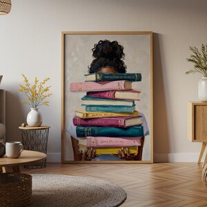 May include: A framed wall art print depicting a person with dark curly hair in a bun, holding a tall stack of colorful books. The top book is dark green with the text The Keeper of Secrets, followed by pink, red, teal, yellow, and purple volumes.