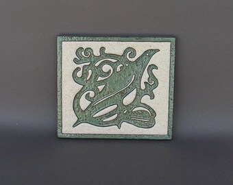 Stoneware trivet with Arts & Crafts design of a bird, embossed and glazed