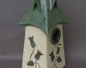 Cream-colored stoneware decorative birdhouse, with green roof with dormers