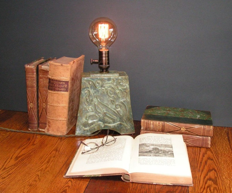 and indented Art Nouveau design of a bird mottled green glaze Stoneware lamp with vintage Edison bulb