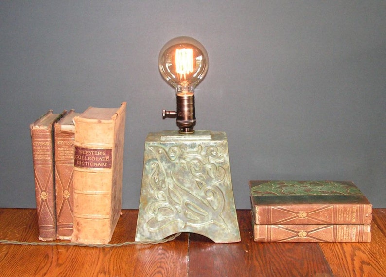 and indented Art Nouveau design of a bird mottled green glaze Stoneware lamp with vintage Edison bulb