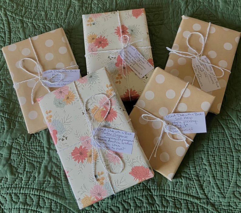 This image shows six of the wrapped up "blind date with a book." Each book is wrapped with brown wrapping paper with white polka dots or floral wrapping paper, white and silver string and has a tag with the genre and a description of the book.