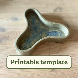 May include: A handmade, ceramic, three-lobed tray with a speckled, earthy exterior and a blue and gold interior. The tray is on a wooden surface. The text "Printable template" is in a green and white banner at the bottom.