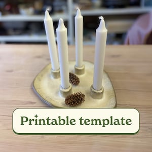 May include: A ceramic candle holder with four white candles and two pinecones. The holder is a light beige color with a textured surface. The text "Printable template" is displayed on a green banner.