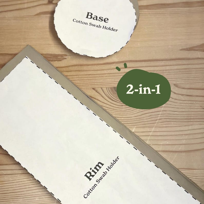 May include: A 2-in-1 cotton swab holder kit with a base and rim. The base is a white circle with the text "Base Cotton Swab Holder". The rim is a white rectangle with the text "Rim Cotton Swab Holder". The kit is on a wooden surface.