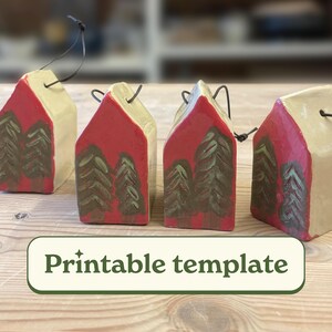 May include: Four ceramic house ornaments with red roofs and cream-colored walls. Each house features a painted forest scene in shades of green and brown. The ornaments have black hanging strings and the text "Printable template".