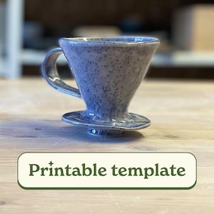 May include: A blue and white ceramic pour-over coffee dripper with a speckled glaze. The dripper is sitting on a wooden surface with the text "Printable template" below it.