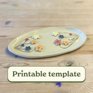 May include: Oval ceramic serving platter with a cream-colored base, adorned with colorful flower designs in red, yellow, orange, and blue. The platter has a hand-painted floral pattern and the text "Printable template".