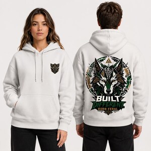 May include: A white hooded sweatshirt featuring a small wolf head graphic on the left chest and a large, detailed wolf head illustration on the back. The back design includes geometric patterns, green and brown accents, and the text BUILT DIFFERENT BORN FERAL.