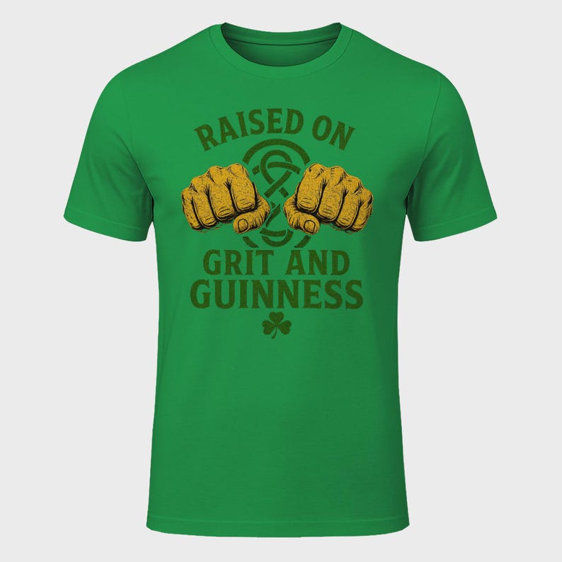 May include: Green t-shirt with the text "RAISED ON GRIT AND GUINNESS" in brown. The design includes two fists, a Celtic knot, and a shamrock. The shirt is a solid green color.