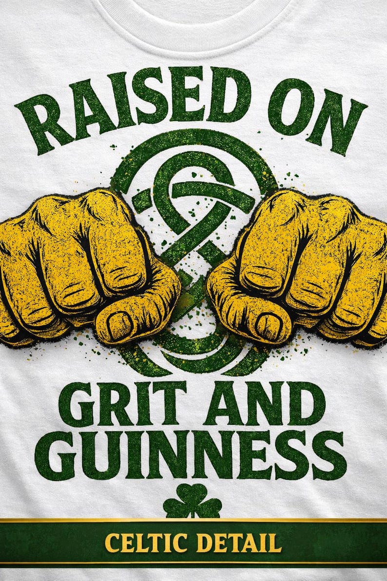 May include: White t-shirt with a green and yellow graphic. The design features two clenched fists, a Celtic knot, and the words "RAISED ON GRIT AND GUINNESS" in green. The bottom of the shirt has the words "CELTIC DETAIL".