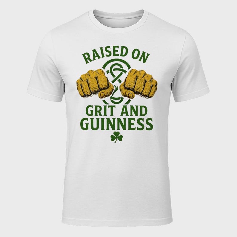 May include: White t-shirt with a green and gold graphic. The graphic includes two fists, a Celtic knot, a shamrock, and the text "RAISED ON GRIT AND GUINNESS".