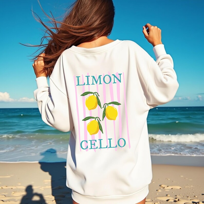 May include: White sweatshirt with a pink and white striped design and three yellow lemons. The text "LIMON CELLO" is printed on the sweatshirt.