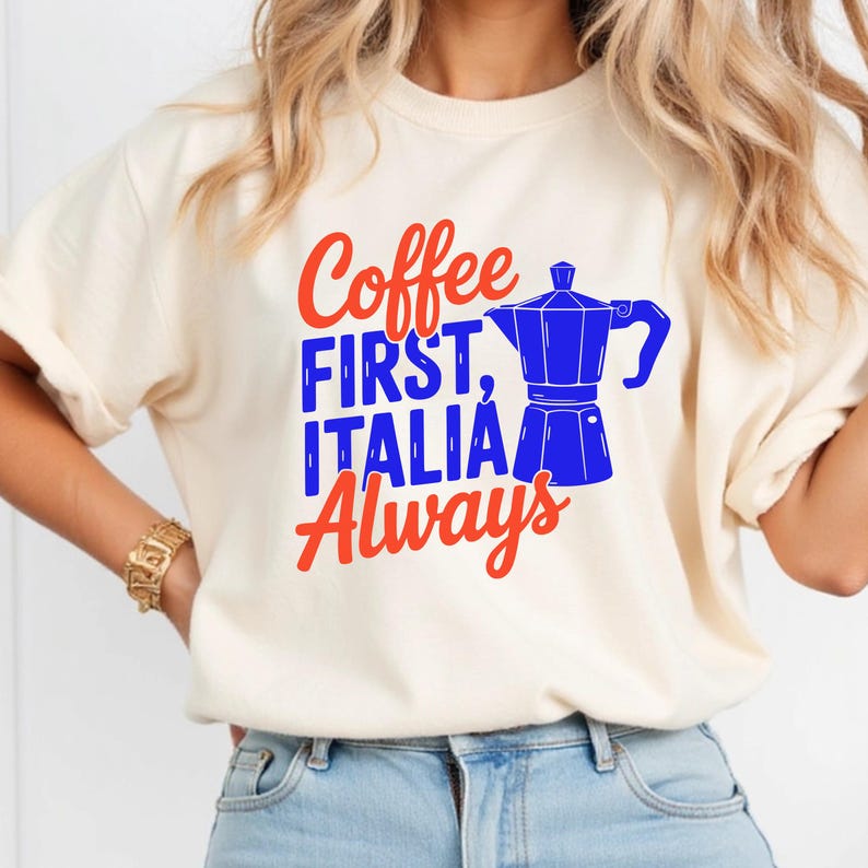 May include: Cream-colored t-shirt with the text "Coffee FIRST, ITALIA Always" in red and blue. A blue coffee pot graphic is next to the text. The shirt is a casual style.