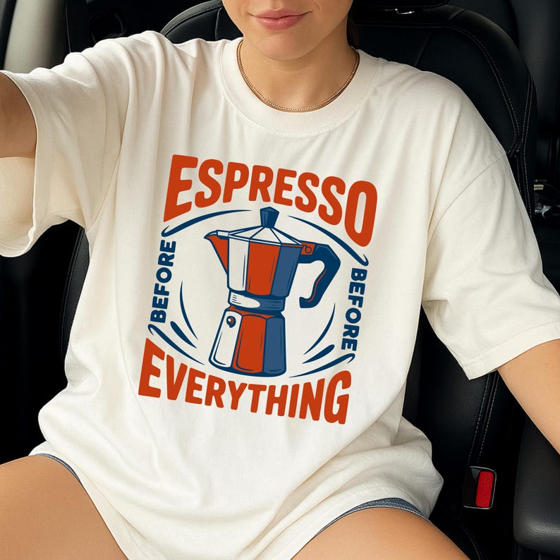 May include: Cream-colored t-shirt with a red, white, and blue graphic of an espresso maker. The text "ESPRESSO BEFORE EVERYTHING" is printed around the coffee pot design. The shirt is a casual, everyday wear item.