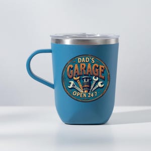 Może przedstawiać: Niebieski kubek termiczny ze stali nierdzewnej z pokrywką. Kubek ma grafikę z vintage'owym znakiem, na kt&oacute;rym widnieje napis "Garage Taty Otwarte 24/7" wraz z narzędziami i częścią samochodową.