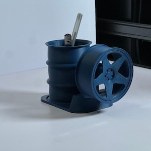 May include: A blue 3D printed desk organizer shaped like a car tire with a smaller cylinder for pens and pencils.