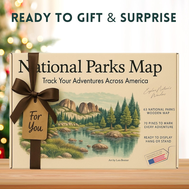 Puede incluir: Un mapa de parques nacionales en caja con una cinta marr&oacute;n y una etiqueta que dice "Para ti". La caja presenta una ilustraci&oacute;n de paisaje de un lago y monta&ntilde;as, con el texto "Sigue tus aventuras por Am&eacute;rica". La caja tambi&eacute;n dice "Listo para regalar y sorprender".
