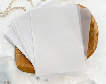 May include: A stack of white translucent paper sheets on a wooden tray. The paper is smooth and has a slight sheen. The tray is made of light brown wood and has a natural finish.
