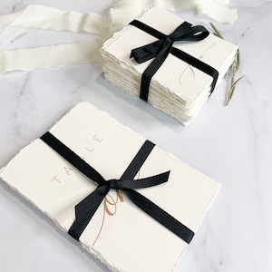 a stack of white cards with a black ribbon