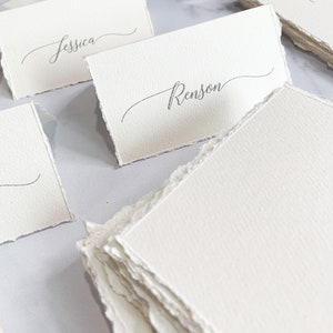 a table topped with lots of white place cards