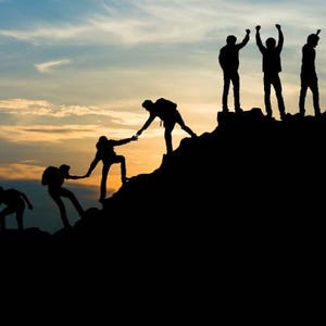 Könnte beinhalten: Silhouetten von Menschen, die bei Sonnenuntergang einen Berg besteigen. Sie helfen sich gegenseitig, den Gipfel zu erreichen. Der Himmel ist in leuchtenden Orange- und Rosatönen.