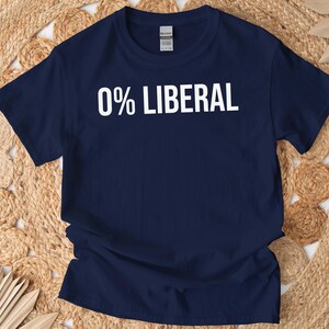 May include: Navy blue t-shirt with the text "0% LIBERAL" in bold white letters. The short-sleeved shirt is made of a soft material and is displayed on a woven, beige surface.