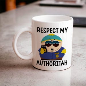 Könnte beinhalten: Weiße Keramik-Kaffeetasse mit einem Cartoon-Bild eines Charakters in Polizeiuniform und Sonnenbrille. Der Text "Respect My Authoritah" ist auf die Tasse gedruckt.