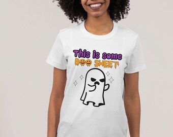 May include: White t-shirt with a Halloween-themed graphic. The shirt features the text "This is some BOO SHEET" in purple and orange, along with a cartoon ghost illustration. Four star shapes surround the ghost.