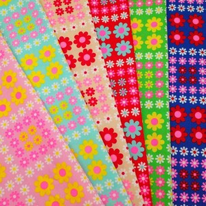 Peut inclure: Six échantillons de tissu différents avec un motif répétitif de fleurs de marguerite colorées. Les tissus sont dans des tons de rose, bleu, vert, rouge et beige.