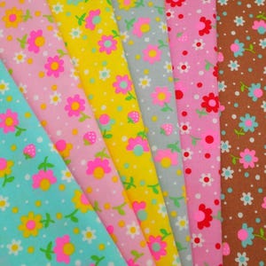 May include: A selection of floral fabric swatches in various colours. The fabrics display patterns with pink, yellow, blue, and brown backgrounds. Each fabric has a repeating pattern of flowers and small white dots.
